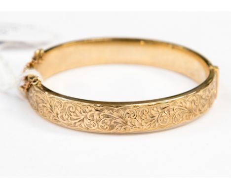 A 9ct gold hinged bangle scroll and leaf engraved decoration, approx 12.2 grams 