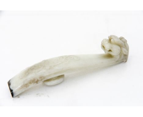 A Chinese carved jade belt hook, modelled as a dragon with relief foliate scroll decoration, the tip highlighted in black, 10