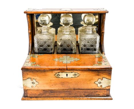 A Victorian oak and brass tantalus, fitted with three decanters, s.d, no key 