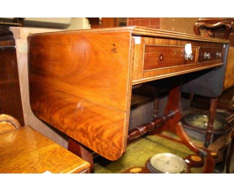 A Regency style mahogany sofa table with two drop leaves, fitted with two drawers, shaped supports and standing on sabre legs