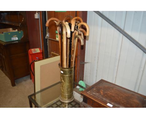 A brass embossed stick stand and a quantity of wooden walking sticks 