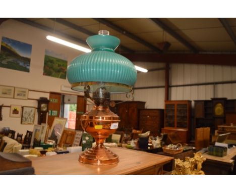 A copper oil lamp with green glass shade