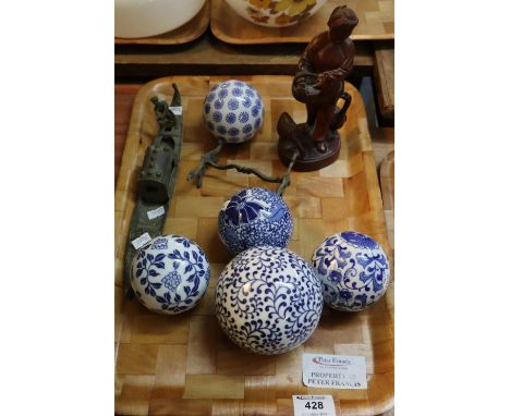 Five blue and white ceramic decorative balls, together with a Japanese carved hardwood study of a figure with basket and bird