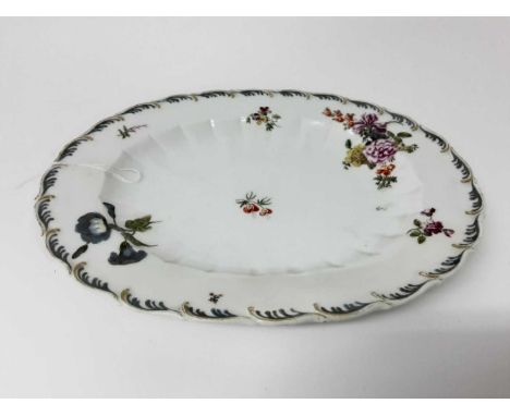 A Chelsea oval dish, circa 1760, sparsely decorated in enamels with floral sprays, wavy rim with gilt and enamel decoration, 