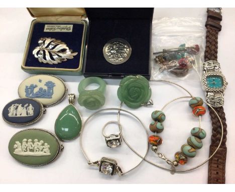 Group of silver and other costume jewellery to include three Wedgwood brooches, green hard stone carved flower ring and penda