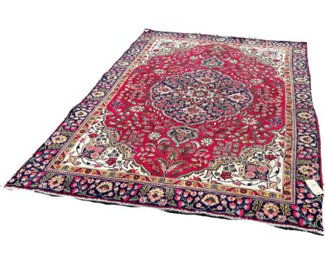 A Tabriz style carpet with a central floral medallion on a floral red ground, 260cm x 180cm approximately