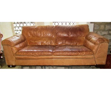 A weathered tan leather two seat sofa, 217cm wide.