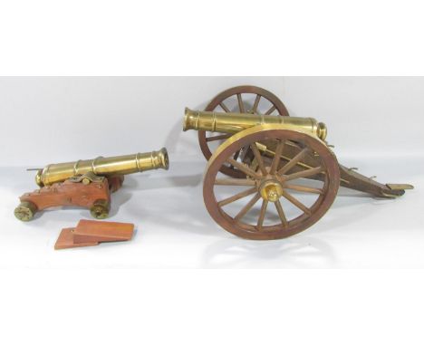 A model brass field canon on a wooden carriage 43cm x 26cm approximately and a ship’s canon, 26cm x 13cm, both with moving pa