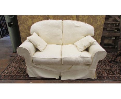 A contemporary two-seat sofa with loose cream covers 