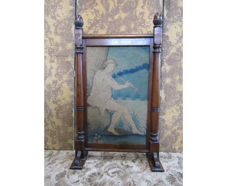 A stained pine framed firescreen with carved acorn finials enclosing a (earlier) embroidered panel detailing a seated piper, 