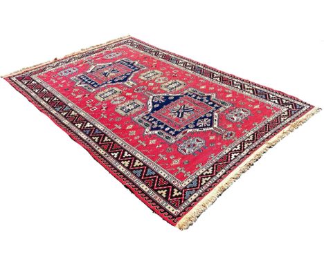 A Middle Eastern flat weave carpet with two lozenge shaped medallions on a pink ground, 275cm x 190cm approximately