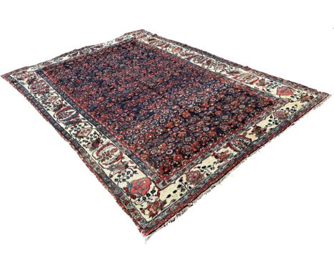 An antique Persian carpet, with an all over floral pattern on a predominantly blue ground and floral borders, 300cm x 210cm a