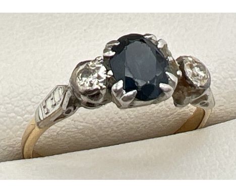 An 18ct gold and platinum, sapphire and diamond trilogy ring - needs repair. Central oval cut sapphire with a small round cut