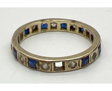 An Art Deco style full eternity ring set with blue and clear stones (one blue stone missing). No gold marks by tests as 9ct g