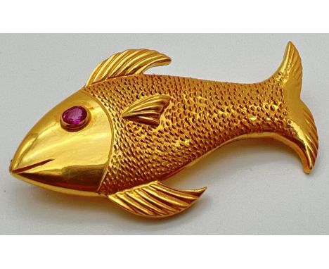A 22ct gold brooch in the shape of a fish set with oval cut ruby eye. Patterned detail to body with ridged decoration to fins
