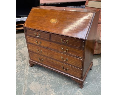 A George III mahogany bureau, the fall front with central shell marquetry inlay, opening to a fitted interior, over two short
