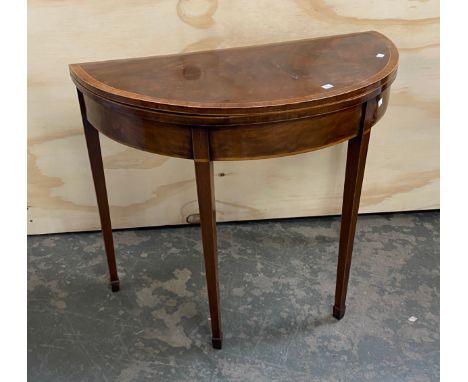 A George III mahogany and cross banded demi-lune card table, the foldover top on square tapered line inlaid legs with spade f