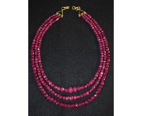 A three strand faceted ruby bead necklace, three tapering graduated strands of pinky red rubies ranging from approx 4.7mm to 