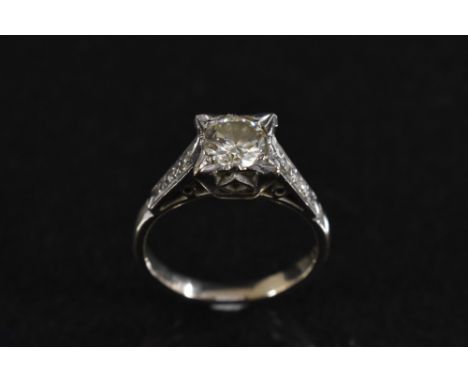 A diamond solitaire ring, round old brilliant cut diamond approx 1.0ct, within Art Deco box claw crown, between diamond accen