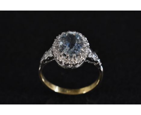 A diamond and pale blue stone cluster ring, central oval pale blue stone possibly topaz, surrounded by a sixteen round cut di