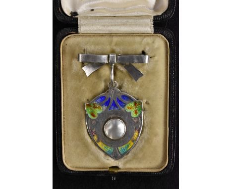 An Edwardian Art Nouveau enamelled silver shield pendant, mother of pearl disc centre, multi-colour enamel panelled surround,