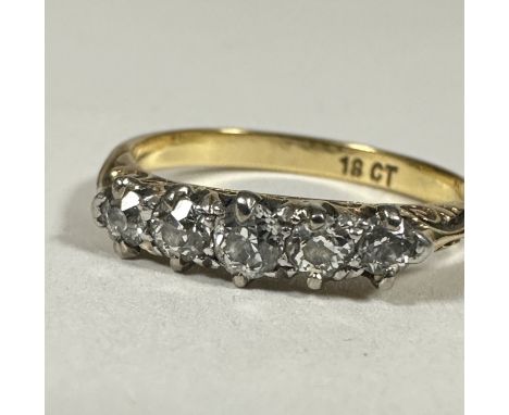 A 18ct gold graduated five stone Diamond ring, the old cut stones mounted in white metal claw settings and pierced scroll mou