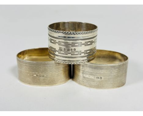 A pair of Birmingham silver oval engine turned napkin rings and Sheffield silver napkin ring with engined turned design, all 