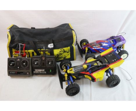 Two Tamiya 1/10th scale Dirt Thrasher remote control cars complete with battery chargers and remote controls stored within a 