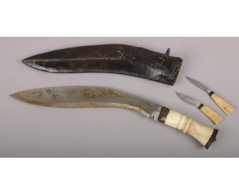 A gurkha's kukri knife in scabbard with carved bone grip and two smaller accompanying knives.  