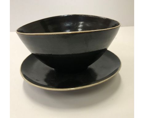 A Lucie Rie and Hans Coper black glazed elliptical bowl and saucer, both bearing both marks, the bowl 14 cm x 12 cm x 7 cm hi