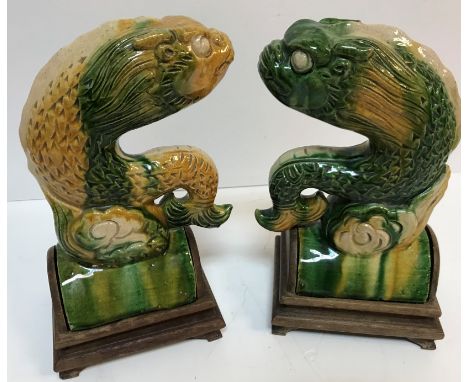 A pair of 19th Century Chinese Sancai yellow and green glazed pottery ridge tiles as stylised fish with dragon heads in the M