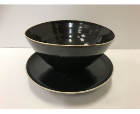 A Lucie Rie and Hans Coper black glazed elliptical bowl and saucer, both bearing both marks, the bowl 13.5 cm diameter x 13 c