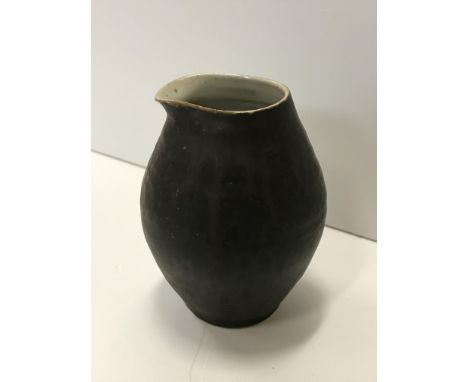 A Lucie Rie pouring vessel, with black glazed exterior and simple design, bears Lucie Rie mark to base, 9.5 cm high (ARR) CON