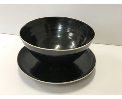 A Lucie Rie and Hans Coper black glazed elliptical bowl and saucer, the bowl bears no maker's marks, 13.5 cm x 13 cm x 6.5 cm