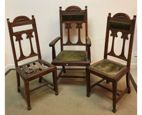 A set of three Art Nouveau oak dining chairs, the carved and inlaid backs with stylised tulip decoration over an upholstered 
