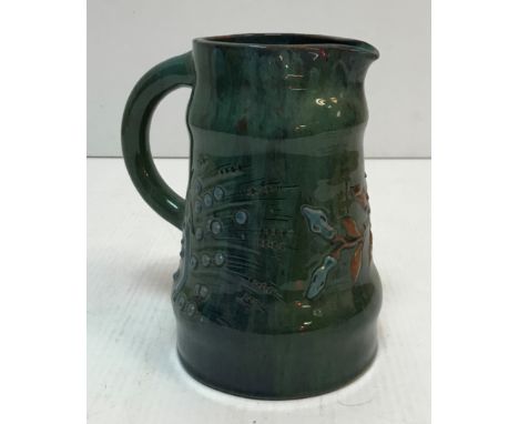 An Elton Pottery jug with relief work floral spray decoration on a deep green blue ground 19 cm high CONDITION REPORTS Has cr