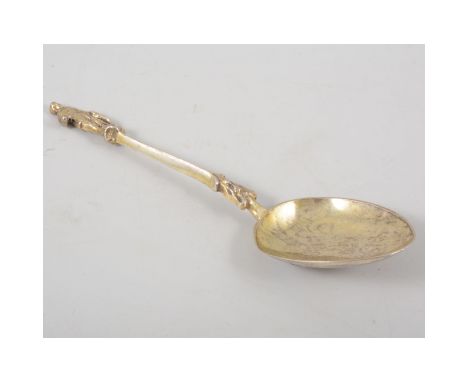 A continental white metal decorative spoon, gilded bowl with crest to underside, standing figure to finial, 17cm, approximate