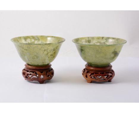 A pair of modern seaweed jade bowls, 10cm diameter, 5cm high, with small wooden stands.