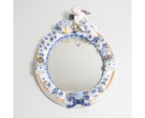 A mirror with blue and white ceramic frame, putti to top and candle holder to each side, overall 28cm x 20cm.