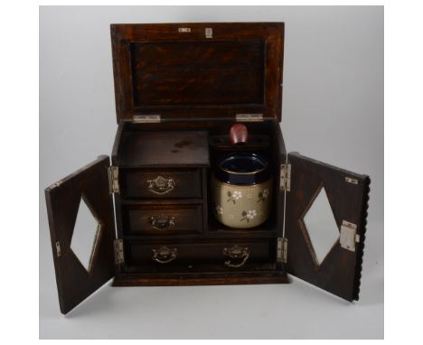 Oak smoker's cabinet, enclosing a Stoneware tobacco jar, 29cm.