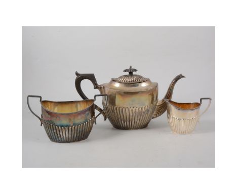 A Victorian silver three piece teaset, oval half fluted body with ebony handle and finial to teapot, gilded interiors to milk