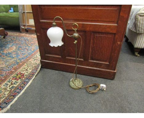 A brass lamp with opaque glass shade