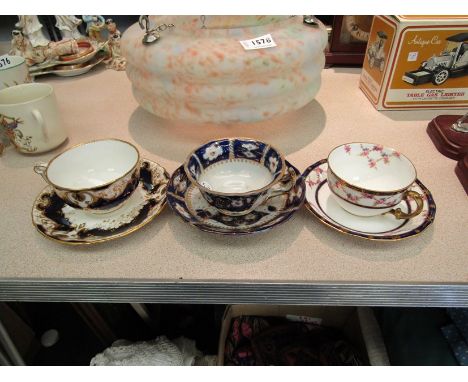 Two Royal Crown Derby porcelain cups and saucers in floral design with blue borders. A similar Continental porcelain cup and 