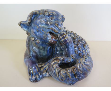 A Chinese stoneware model of dog of Fu decorated in a blue and red glaze, one tooth missing otherwise good - 18cm W 