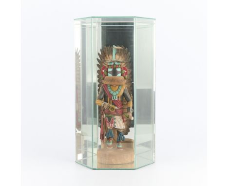 Carved wooden Hopi kachina figure with painted details depicting a form dressed in elaborate indigenous regalia with a bell i