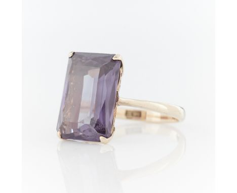 14k yellow gold ring set with a likely synthetic color change Alexandrite-like modified step cut sapphire. Stone is predomina