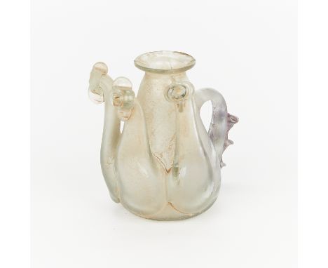 Small early Roman style glass pitcher vessel. With three shapely heads and a ridged handle.Height: 3 1/2 in x width: 3 in x d