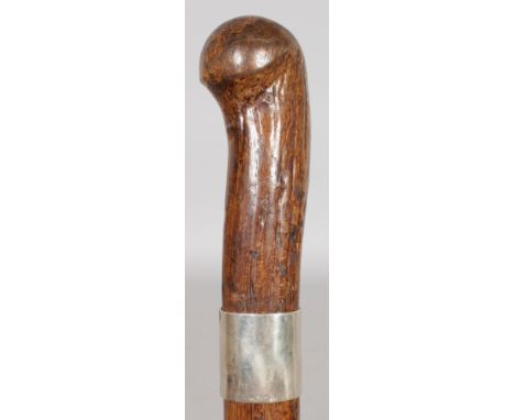 A WOODEN STICK SILVER BAND KUBAND.  37ins long.