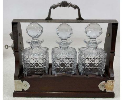A silver plate mounted three bottle tantalus, with locking arm and three hobnail cut glass decanters, length 34cm, complete w