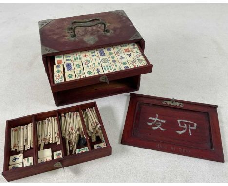 A Mahjong set, with one hundred and forty-four bone and bamboo tiles, in a cabinet set with drawers.Condition Report: The dra